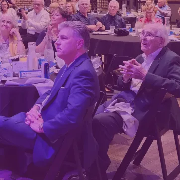 Photo shows group of people at a dinner including Cal Fercho and son in the center.
