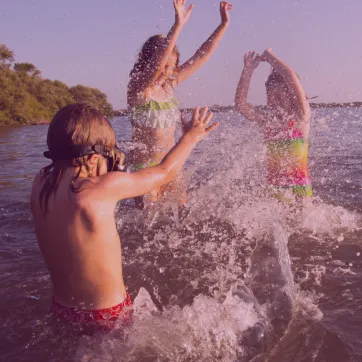 Three kids splashing in the lake